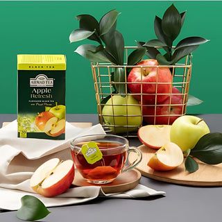 Ahmad Apple Refresh tea brewed with slice of apple and basket of apples on table