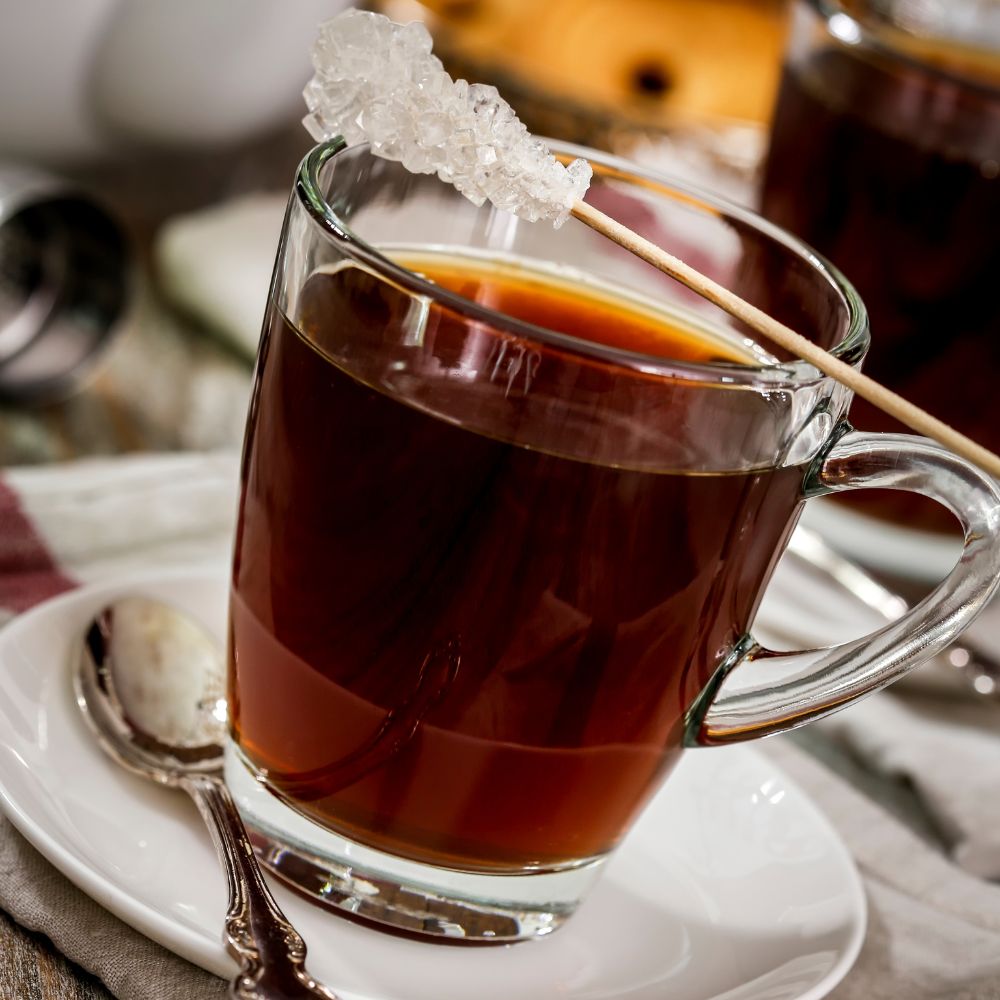 Cup of black tea with a sugar crystal stick on top