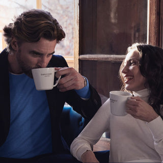 A young couple drinking from Davidoff logo mugs